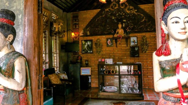 Een klassiek interieur met houten plafond, een kroonluchter en een beeldhouwkunstwerk.