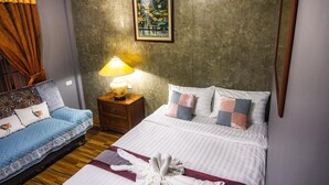 Een hotelkamer met een bed, een bank, een nachtkastje met een lamp en een schilderij aan de muur.