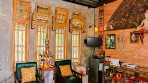 Een kamer met traditioneel houten meubilair, een televisietoestel en een beeld.