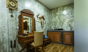 Un bagno con un mobile vanitario in legno, una sedia, uno specchio, una sveglia a parete e un elemento decorativo.