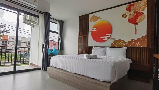 A hotel room with a large bed, a view of the outside, and a decorative wall with traditional elements. - Chalalai Hotel Krabi (Nuea Khlong)