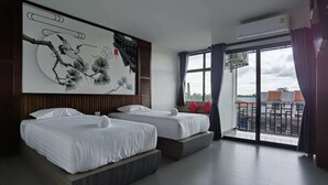 A hotel room with two beds, a large wall painting, a sliding glass door to the balcony, and an air conditioning unit. - Chalalai Hotel Krabi (Nuea Khlong)