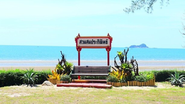 Une plage avec un banc et un panneau devant l’eau.