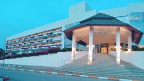 L’entrée d’un hôtel avec un escalier couvert, un bâtiment moderne doté de balcons et un ciel dégagé.