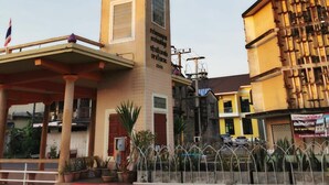 Una torre del reloj con un balcón, rodeada de edificios y una barrera a rayas rojas y blancas.