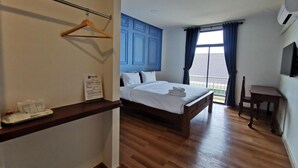 Habitación de hotel con cama de madera, un escritorio, una silla y vistas al exterior.