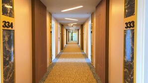 A hotel hallway with numbers 334 and 333 on the walls, carpeted floors, and a ceiling with linear lighting. - Grandview Landmark Betong Hotel (Betong)