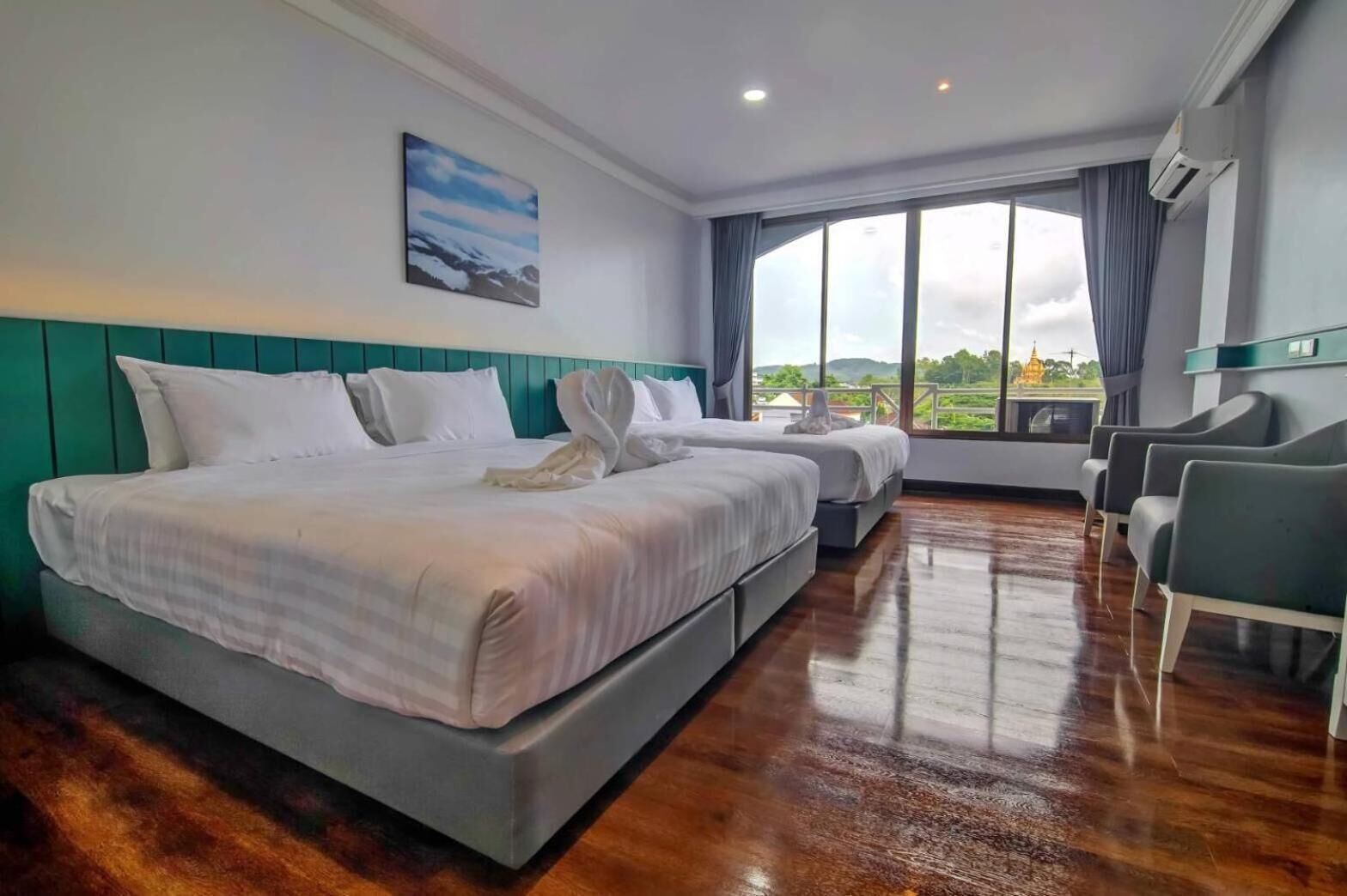 A hotel room with a large bed, a smaller bed, and a seating area with chairs.