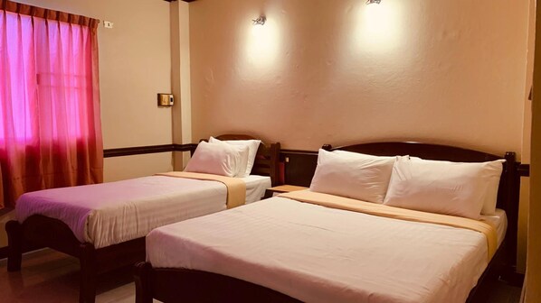 Quarto de hotel com duas camas de solteiro, cabeceira de madeira, janela com cortinas rosa e luminária fixada na parede.