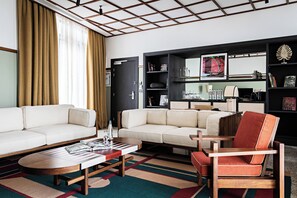 A modern living room with a sofa, armchairs, a coffee table, and a bookshelf. - La Maison Palmier (Abidjan)