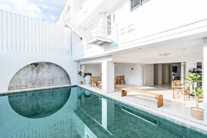 A modern indoor pool area with a clear view of the pool, wooden seating, and a staircase leading to an upper level. - Bedline Hotel - SHA Certified (Phuket)