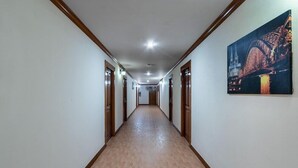 A long, narrow hallway with wooden trim and a tiled floor, leading to a door at the end. - Jb Green Patong (Krabi)