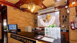 A hotel reception area with a wooden reception desk, a monitor, and a large globe sign. - Jb Green Patong (Krabi)