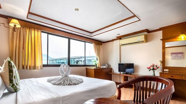 A hotel room with a bed, a desk, a TV, and a view of a bridge. - Jb Green Patong (Krabi)