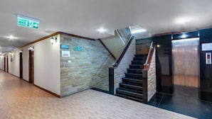 A hotel corridor with a staircase, wooden doors, and an elevator. - Jb Green Patong (Krabi)