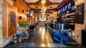 A reception area with a reception desk, potted plants, and a sign reading "JBCAFE". - Jb Green Patong (Krabi)