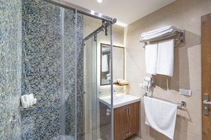 A modern bathroom with a glass shower enclosure, a sink with a mirror, and a towel rack. - Nozol Pyramids Hotel (Giza)