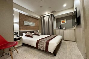 A modern hotel room with a large bed, a red chair, a desk with a telephone, and a flat-screen TV mounted on the wall. - Amand Hotel (Tokyo)