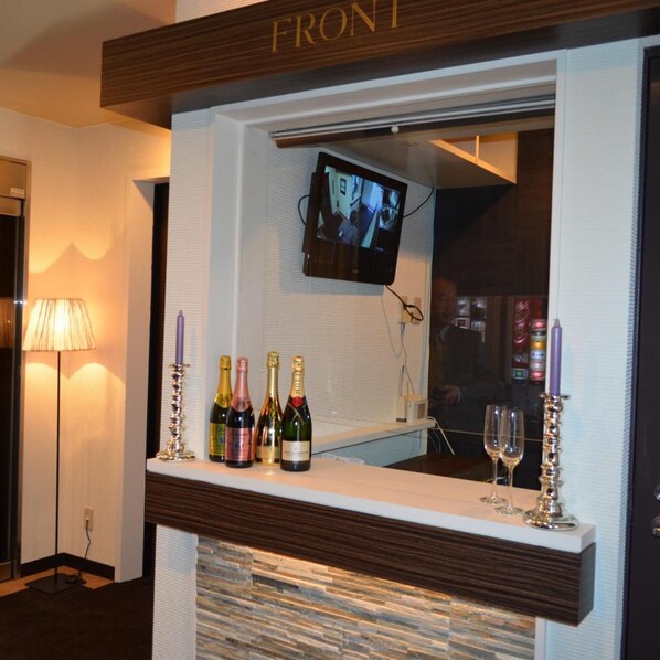 A bar area with a television screen, bottles of champagne, and candles. - Amand Hotel (Tokyo)