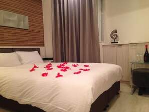 A hotel room with a bed, a nightstand, a chair, a curtain, and a wall-mounted decoration. - Amand Hotel (Tokyo)