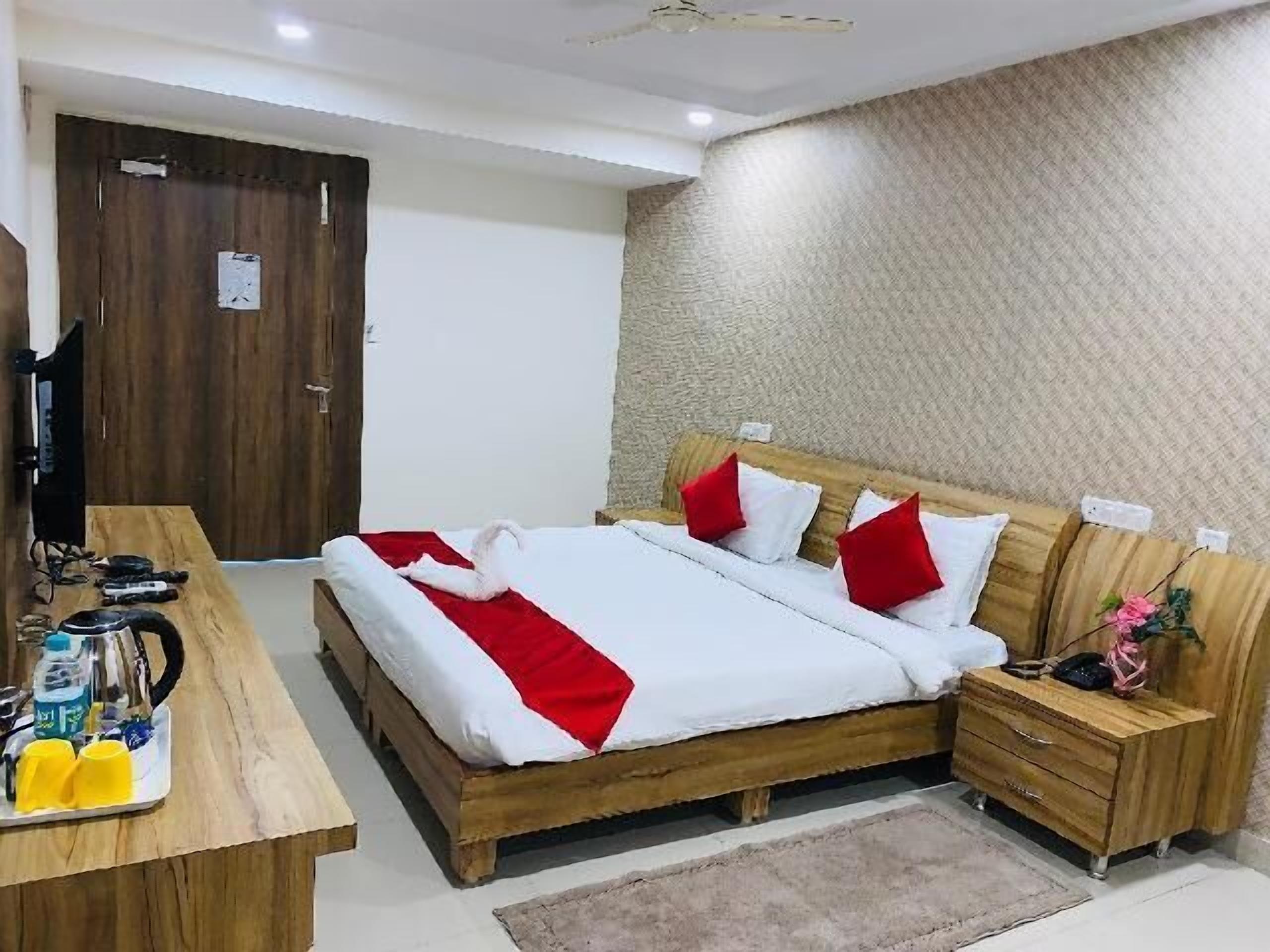 A room with a wooden bed, bedside tables, a wooden desk, and a television.