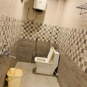 A bathroom with a toilet, shower, and a trash bin. - The Landmark Banjara Hills (Hyderabad)
