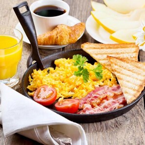 Ein Frühstücksteller mit Rührei, Speck, Toast und einem Glas Orangensaft.