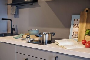 Ett kök med en spis, kastruller, en bok och en skärbräda.