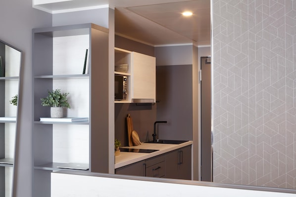 A modern kitchen with built-in appliances, a countertop, and a backsplash. - Candlewood Suites Dusseldorf Airport (Düsseldorf)