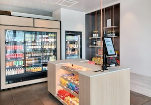 A modern retail area with refrigerated beverage displays, snack shelves, and a self-service checkout. - Candlewood Suites Dusseldorf Airport (Düsseldorf)