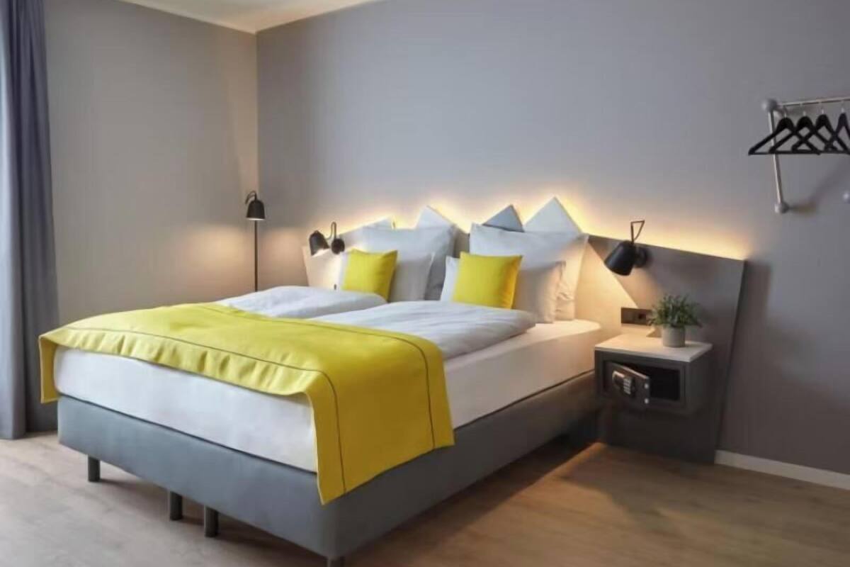 A modern bedroom with a bed, bedside tables, and a wall-mounted lamp.