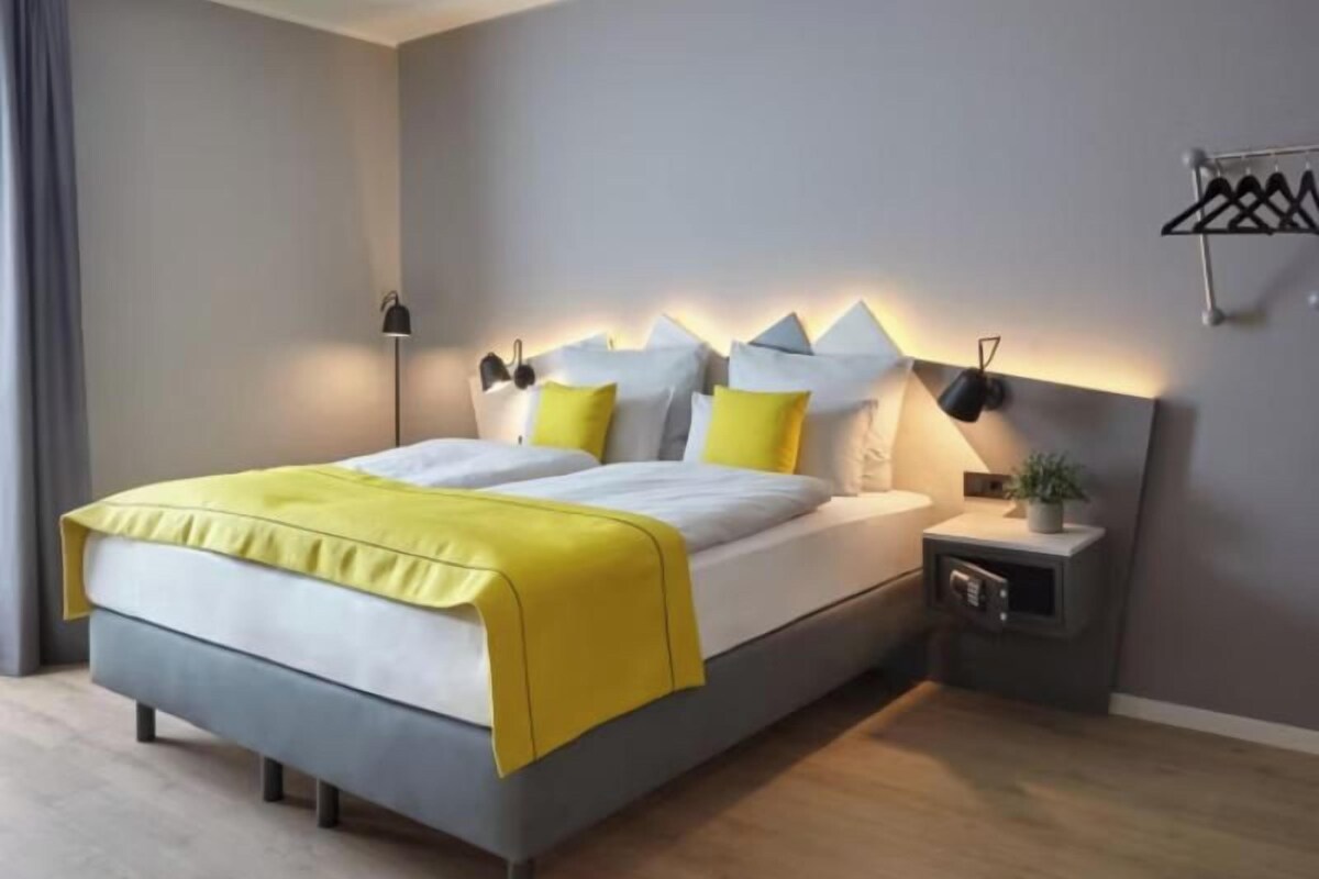 A modern bedroom with a bed, bedside tables, and a wall-mounted lamp.