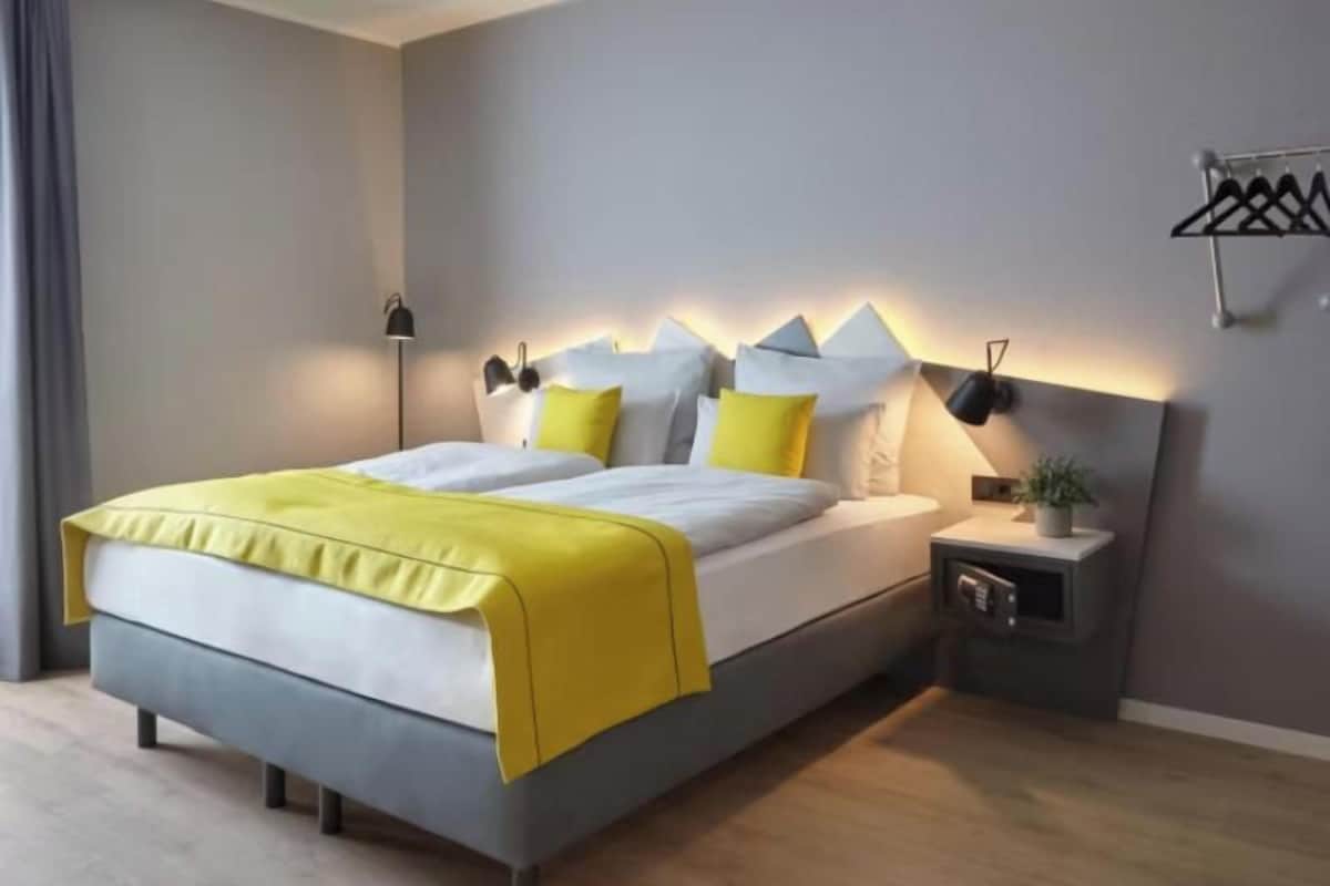 A modern bedroom with a bed, bedside tables, and a wall-mounted lamp.