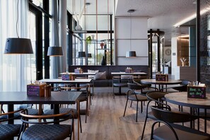 A modern cafe with round tables, black chairs, and pendant lights. - Candlewood Suites Dusseldorf Airport (Düsseldorf)