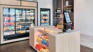 A modern retail area with refrigerated beverage displays, snack shelves, and a self-service checkout. - Candlewood Suites Dusseldorf Airport (Düsseldorf)