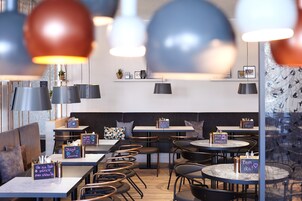 Un café moderno con mesas redondas, asientos acolchados e iluminación colgante.