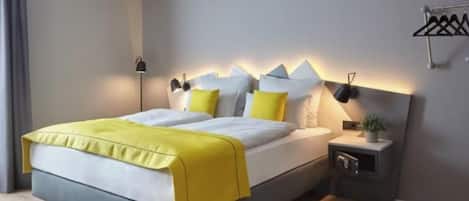 A modern bedroom with a bed, bedside tables, and a wall-mounted lamp.