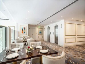 A hotel dining area with tables set for four, chairs, and artwork on the walls. - Shraao Hotel (Doha)