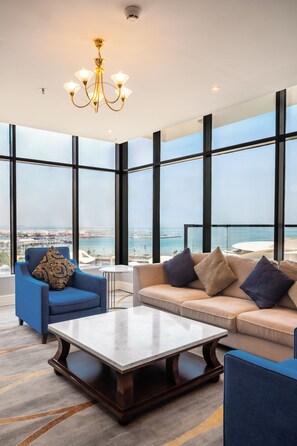 A modern living room with a large window, a chandelier, and a view of the city. - Shraao Hotel (Doha)