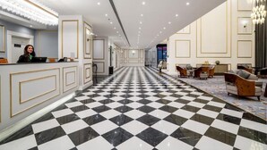 Un hall d’hôtel avec un sol à carreaux, un comptoir d’accueil et un espace détente avec des canapés.