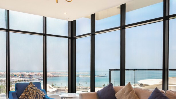 Un salon moderne doté d’une grande fenêtre, d’un lustre et offrant une vue sur la ville.