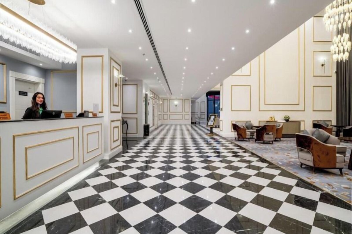 A hotel lobby with a checkered floor, a reception desk, and seating areas.