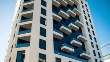Um edifício alto com várias varandas, janelas grandes e um design arquitetônico moderno.