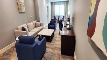 Quarto de hotel com sofá, poltronas, mesa de centro e escrivaninha.