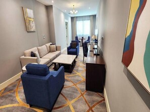 A hotel room with a sofa, armchairs, a coffee table, and a desk. - Shraao Hotel (Doha)