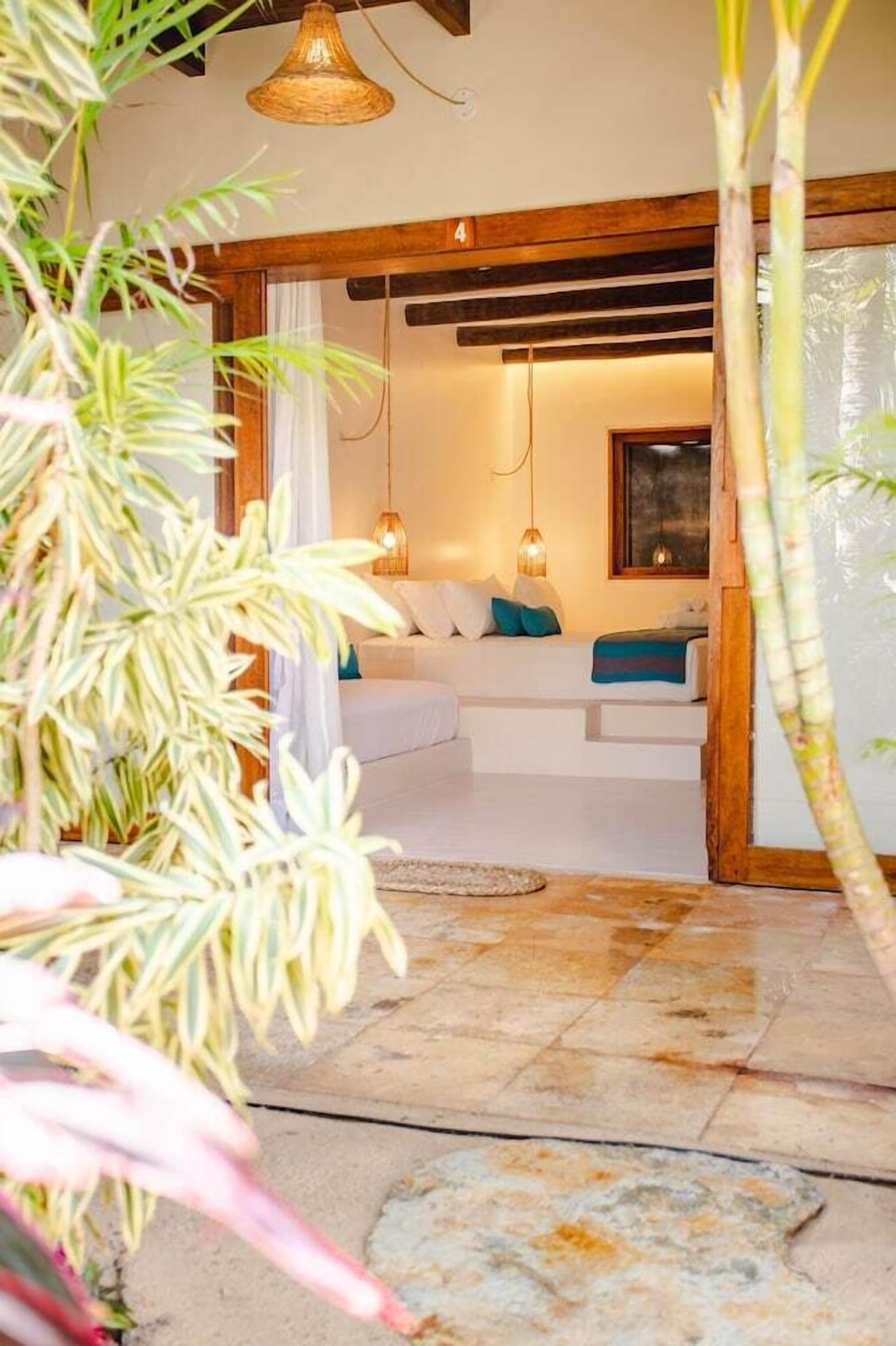 Um quarto acolhedor com cama, luminária pendente e teto de madeira.