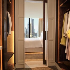 A hotel room with a bed, a view of a cityscape, and a wardrobe with hanging clothes. - The Lana Dubai (Dubai)