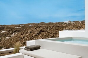 A white infinity pool with a view of rocky terrain and white buildings in the background. - Mykonos Flow Super Paradise (Mykonos)