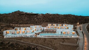 Un hotel modern amb diverses edificacions connectades, una piscina i vista del paisatge rocós circumdant.