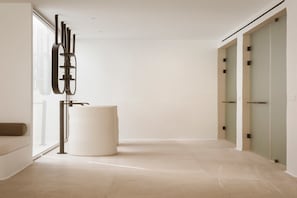 Un intérieur moderne au design minimaliste, comprenant un grand objet cylindrique blanc, une sculpture abstraite noire et une porte en verre.